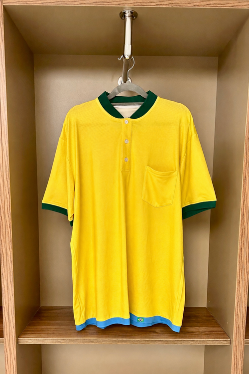 Yellow shirt with green trim hanging in a wooden wardrobe.