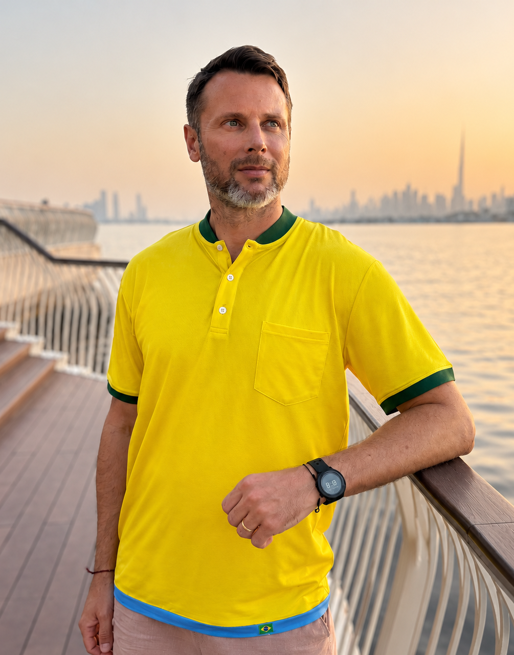 Man wearing a yellow polo shirt with a cityscape in the background