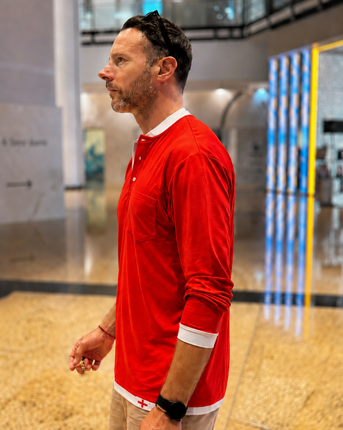 Man wearing a red long-sleeve shirt with white trim in an indoor setting