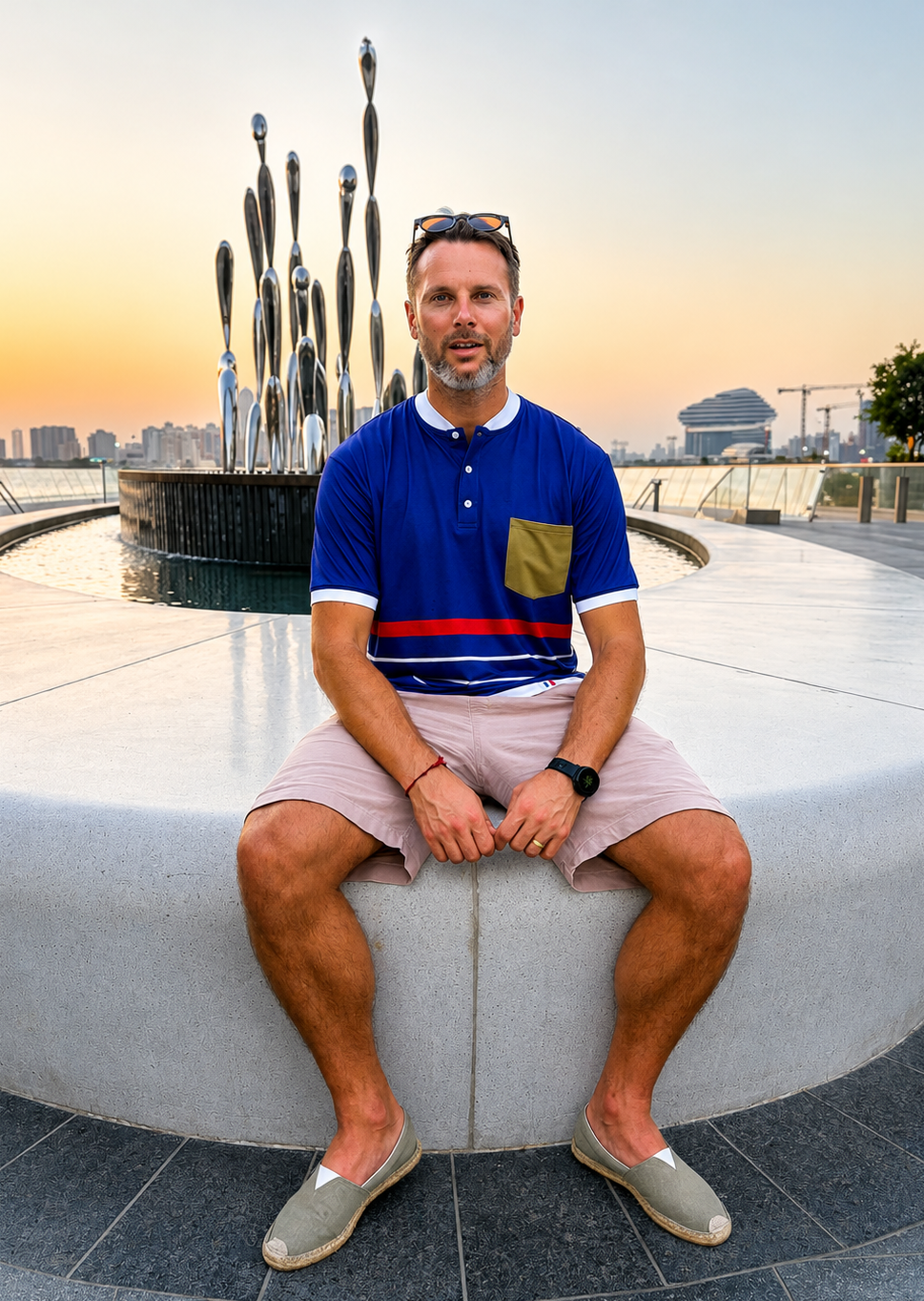 Man sitting on a concrete ledge with a cityscape in the background