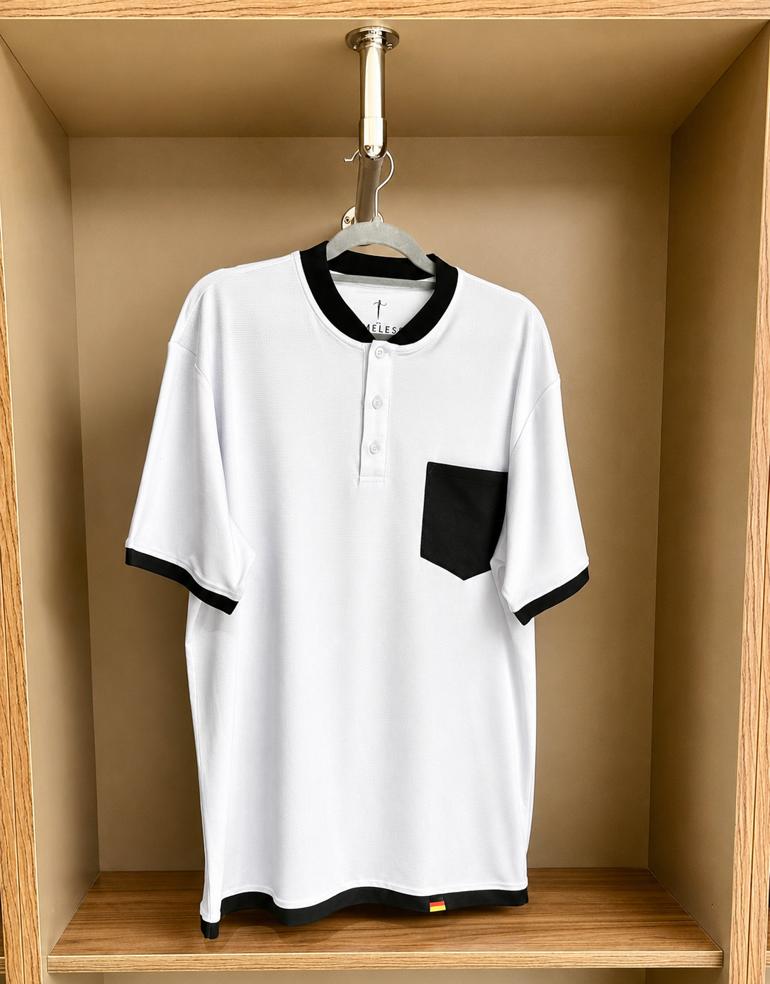 White polo shirt with black accents hanging in a wooden wardrobe.