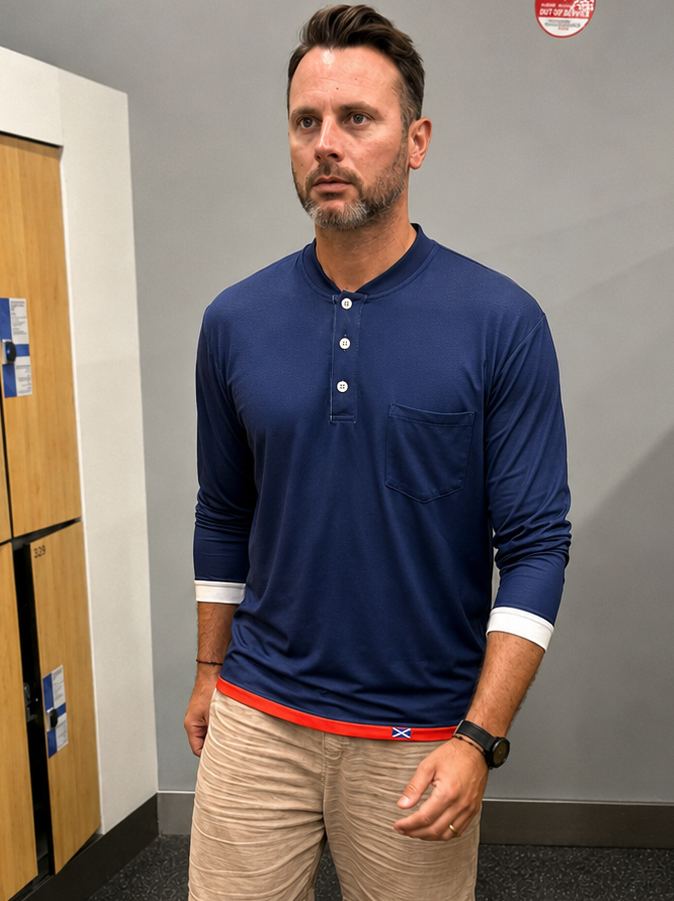 Man in a locker room wearing a blue long-sleeve shirt and beige shorts.