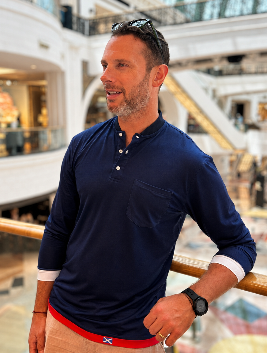 Man wearing a navy blue shirt with a red stripe and beige pants in a mall setting